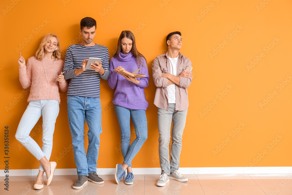 Fototapeta premium Young people waiting in line near color wall