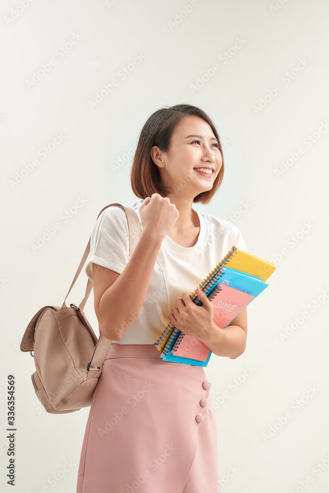 Young happy attractive asian student smiling to camera expression winner by raising hand and arm up to celebrate success on white Young happy attractive asian student smiling to camera expression winner by raising hand and arm up to celebrate success on white