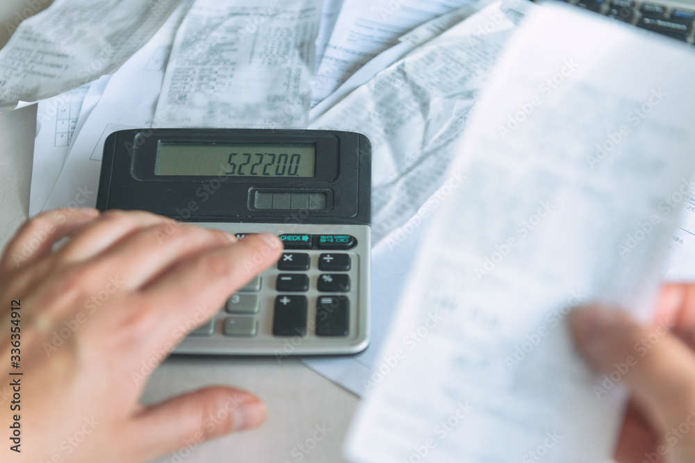 Woman uses a calculator to sum up expenses Woman uses a calculator to sum up expenses