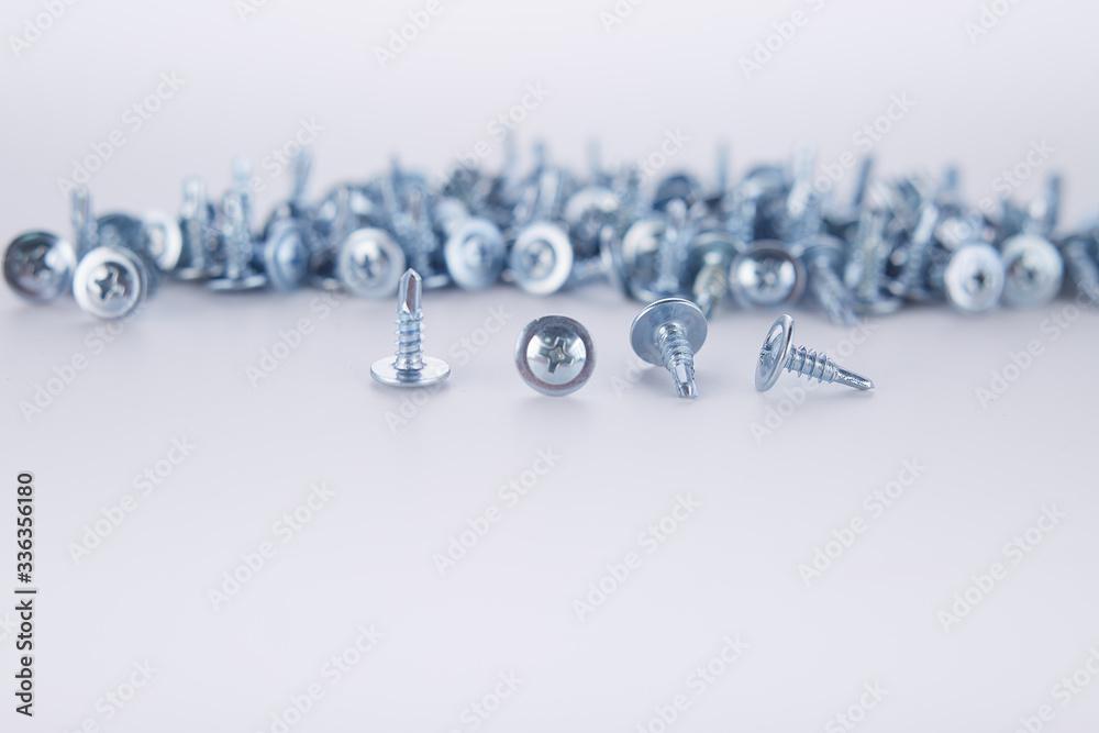 Steel screws in large quantities on a white background Steel screws in large quantities on a white background