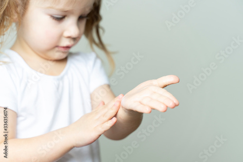 little girl 4 years old in a white T-shirt rubs the sanitizer on her hands. hand treatment in the conditions of the emulsion of coronavirus KOVID-19 photo