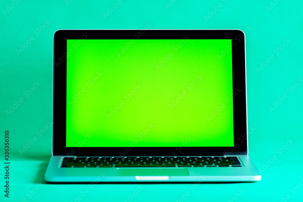 Silver laptop with a green screen on stands on a green background