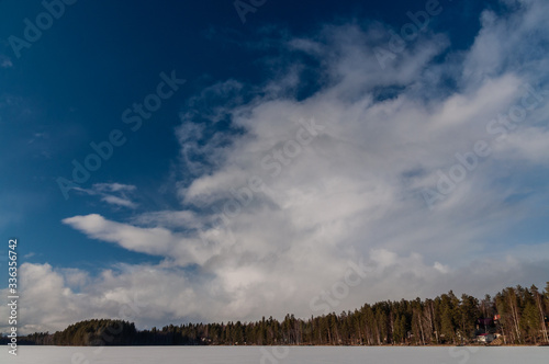 winter landscape with a frozen lake and clouds above it
