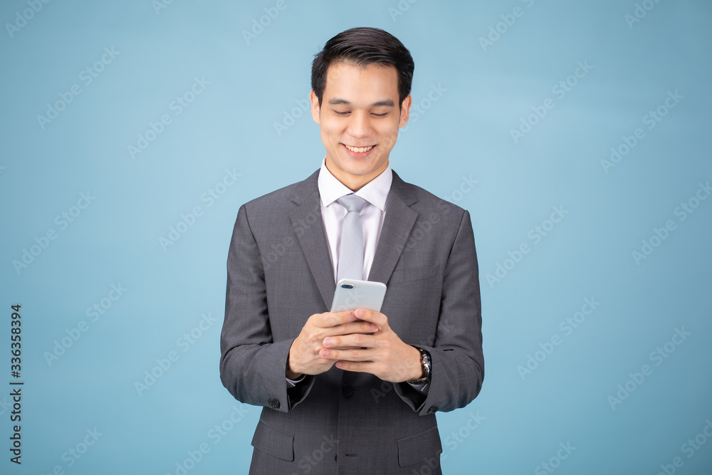 Portrait of smiling Asian Businessman holding and using tablet. Blue background studio concept.
