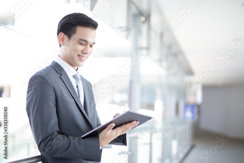 Portrait of confident modern young businessman wear black suit hand holding digital tablet.  photo