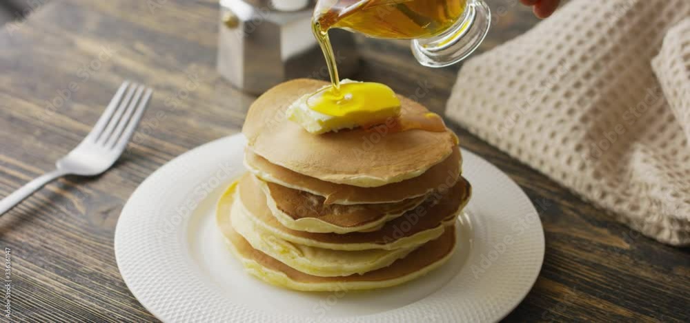 Food and Cooking Concept. Stack of pancakes with butter and warm maple syrup in slow motion Food and Cooking Concept. Stack of pancakes with butter and warm maple syrup in slow motion