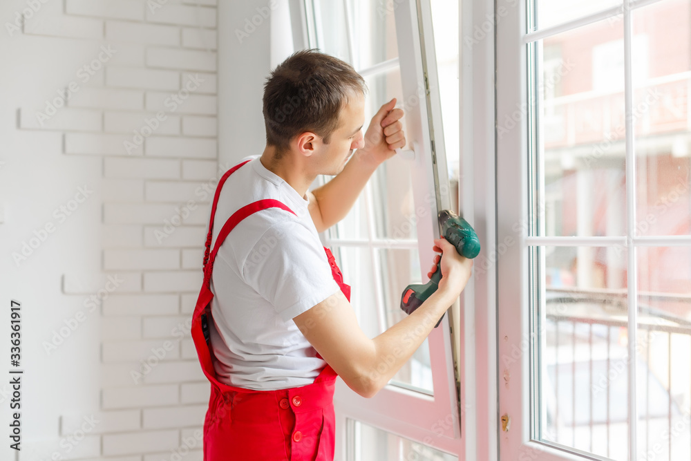 Construction worker installing new window in house Construction worker installing new window in house