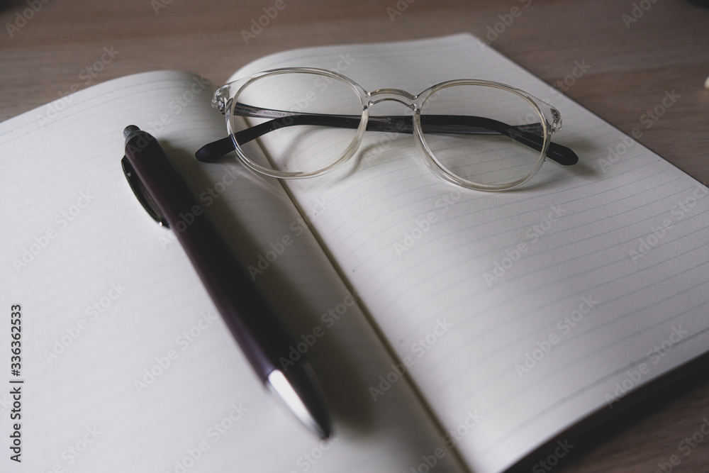 notebook and pen and glasses on the table notebook and pen and glasses on the table