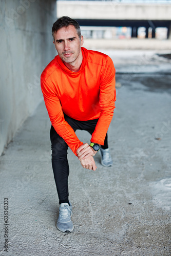 Young runner stretching and warming up for running while standing on the bridge. Urban life scenery. Exercise alone.