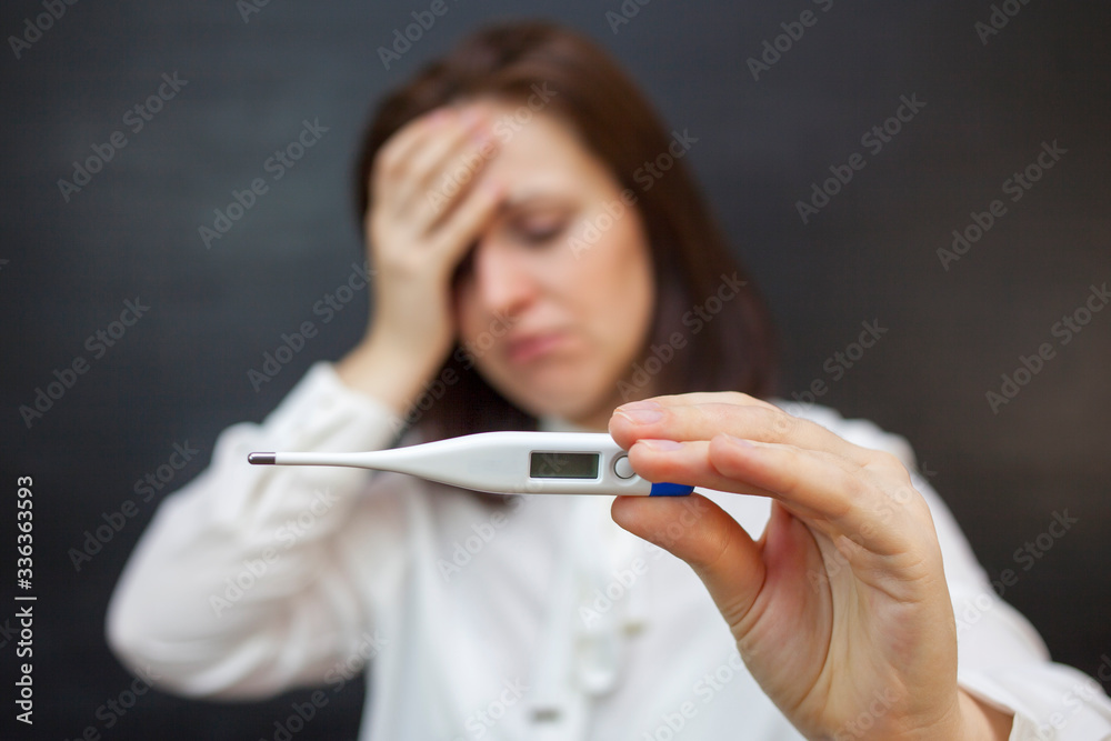 woman with in shock looks at a thermometer. portrait on a black background. woman with in shock looks at a thermometer. portrait on a black background.