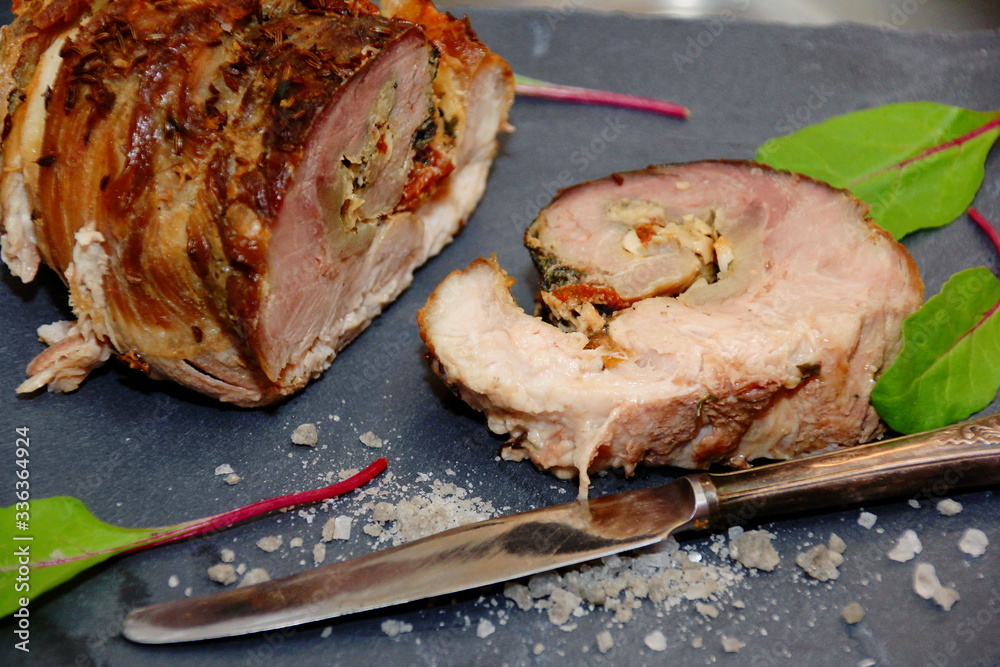 Stuffed meat roll, cut and decorated with new beet leaves, coarse salt and an old knife on a black stone plate Stuffed meat roll, cut and decorated with new beet leaves, coarse salt and an old knife on a black stone plate