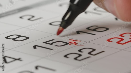 CLOSE UP: Marking a pay day in a paper calendar by red pen