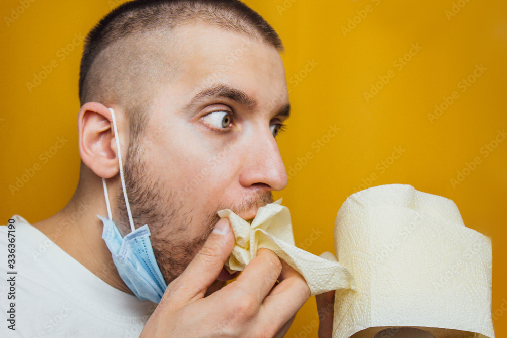 Funny caucasian young man eats a toilet paper. He forgot to buy food in  coronavirus panic. Studio shot. Stock Photo | Adobe Stock