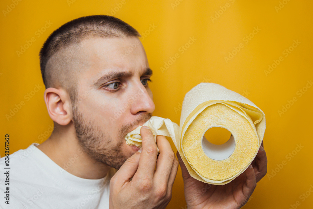 The guy eagerly eats toilet paper. The concept of overbought toilet paper  during coronavirus. Panic, pandemic, virus. Stock Photo | Adobe Stock