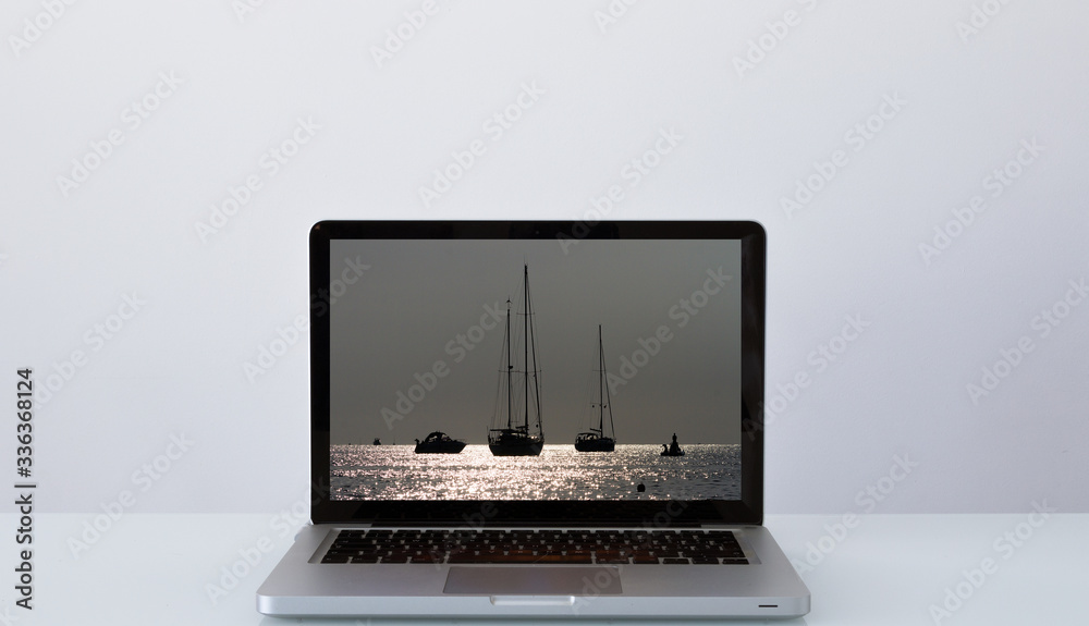 Open laptop with the image of sailboats at sunset Open laptop with the image of sailboats at sunset
