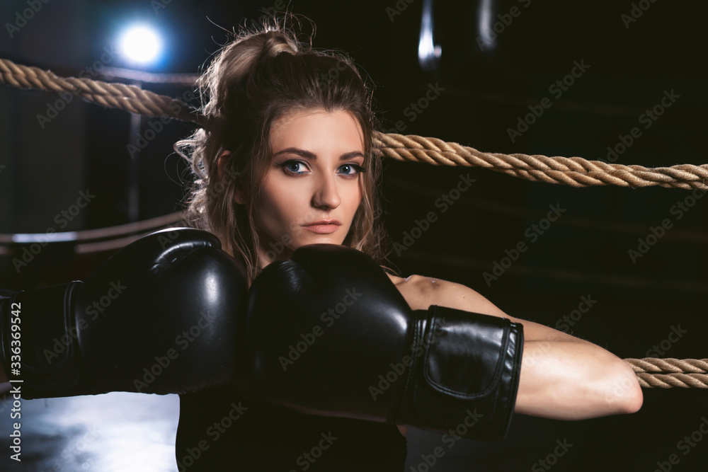 Close up portrait of a young sportswoman in boxing gloves. Pretty female boxer. Healthy lifestyle concept. Girl fighter