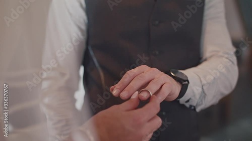 Bride putting on a wedding ring on groom's hand photo