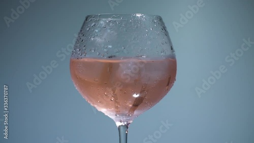 Shot of glass of wine with moving ice cubes in it photo