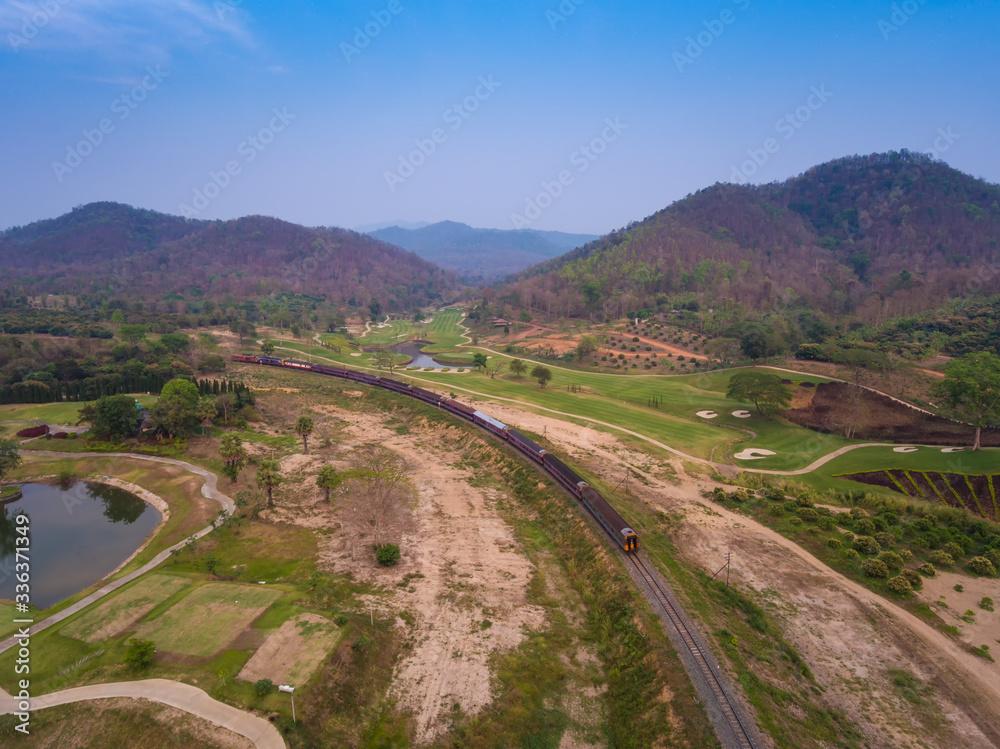 Aerial view train is running through the golf course. There are beautiful bridges in Thailand.
