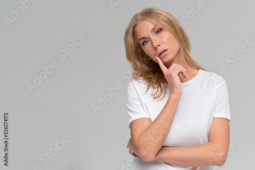 Close up portrait of bored young woman in white t-shirt throw their hands up, staring with indifferent, watching tv at home during quarantine, dont know what do, feel sad, isolated on gray background