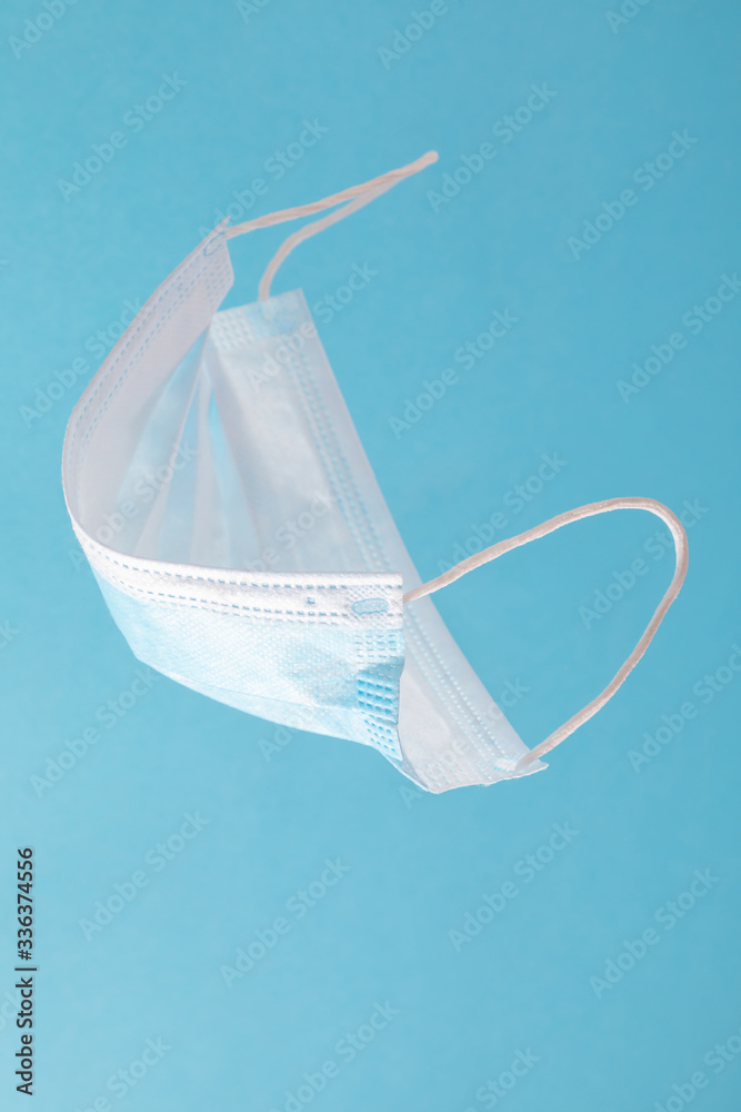 Medical face mask on blue background. Minimal medical concept. Disposable surgical face mask. Flat lay, top view, copy space Medical face mask on blue background. Minimal medical concept. Disposable surgical face mask. Flat lay, top view, copy space