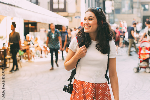 Фотография Happy young tourist woman exploring the lively city