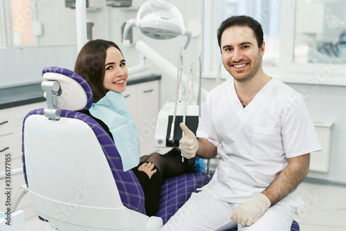 Portrait of a friendly smiling male dentist with patient in the office of a modern dental clinic.