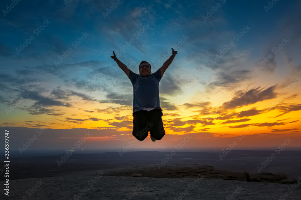 Happy Man jumping silhoutte poses with beautiful sunset background in Edge of the world Riyadh Saudi Arabia. Selective focused on the subject. Happy Man jumping silhoutte poses with beautiful sunset background in Edge of the world Riyadh Saudi Arabia. Selective focused on the subject.