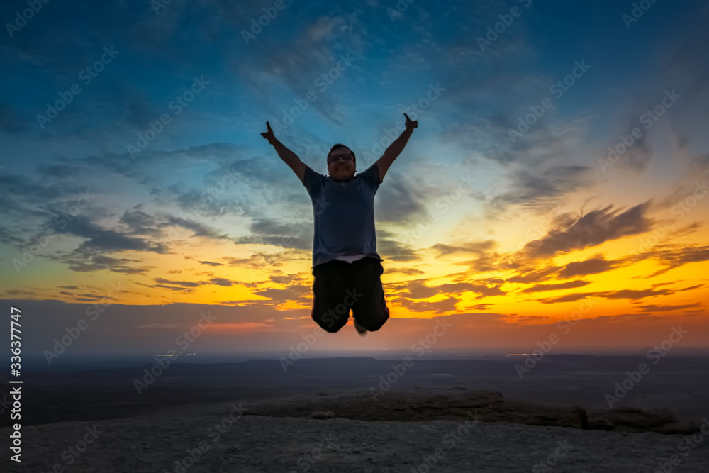 Happy Man jumping silhoutte poses with beautiful sunset background in Edge of the world Riyadh Saudi Arabia. Selective focused on the subject.