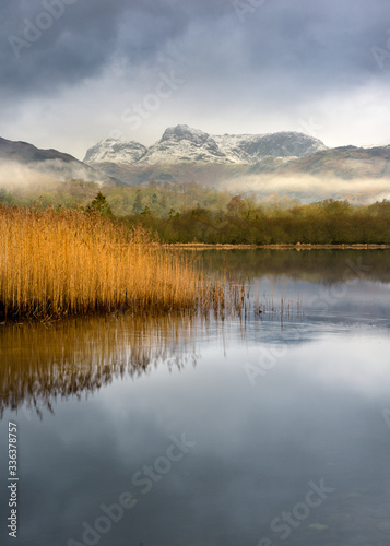 Fototapeta Naklejka Na Ścianę i Meble -  Peaceful Winter Morning With Snow On Mountains Reflecting In Calm Water, Lake District National Park, United Kingdom.