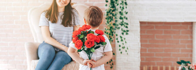 Boy holding a bouquet of flowers behind his back, the son gives his mother flowers, what to present to his mother for his birthday, March 8, mother's day
