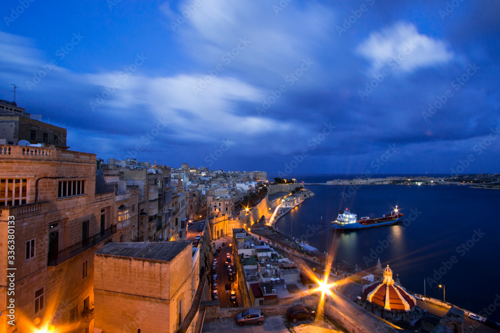 Panoramic night view of the Grand Harbour (Il-Port il-Kbir) of Valletta, Malta, seen from the Upper Barrakka Gardens on the upper tier of the St. Peter & Paul Bastion