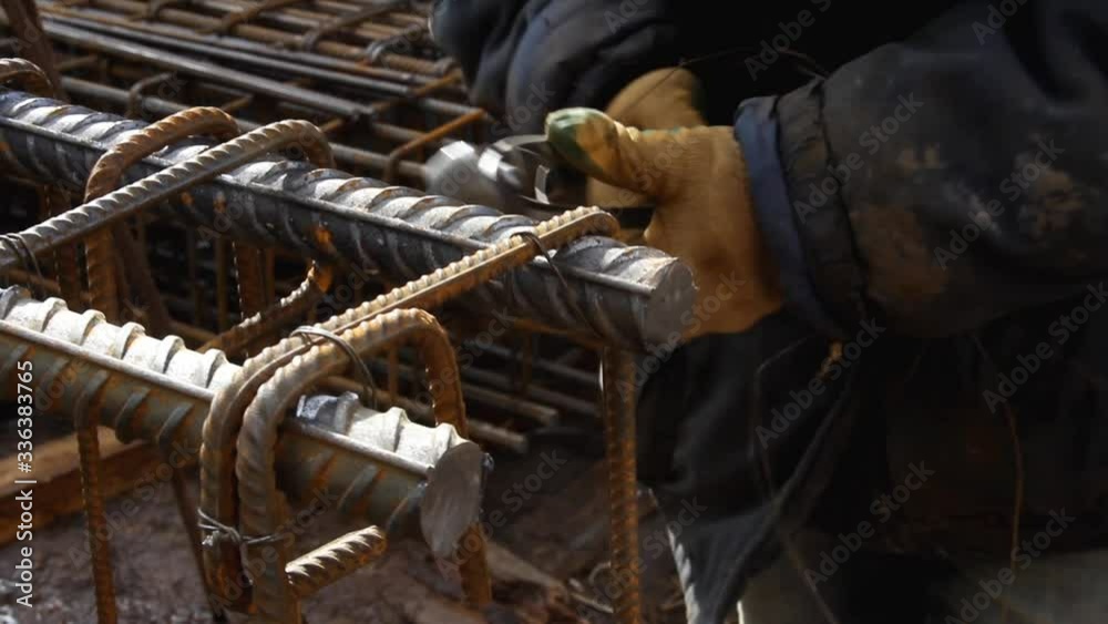Worker hands use pincers tool and iron wires for knitting metal rods.  Pliers for attaching the rebars to each other. Concrete reinforcement.