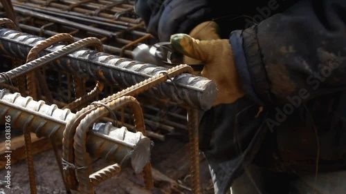 Worker hands use pincers tool and iron wires for knitting metal rods.  Pliers for attaching the rebars to each other. Concrete reinforcement.