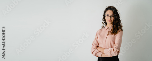 Fotografie Mujer joven con camisa rosa pastel y gafas de vista posando con brazos cruzados,