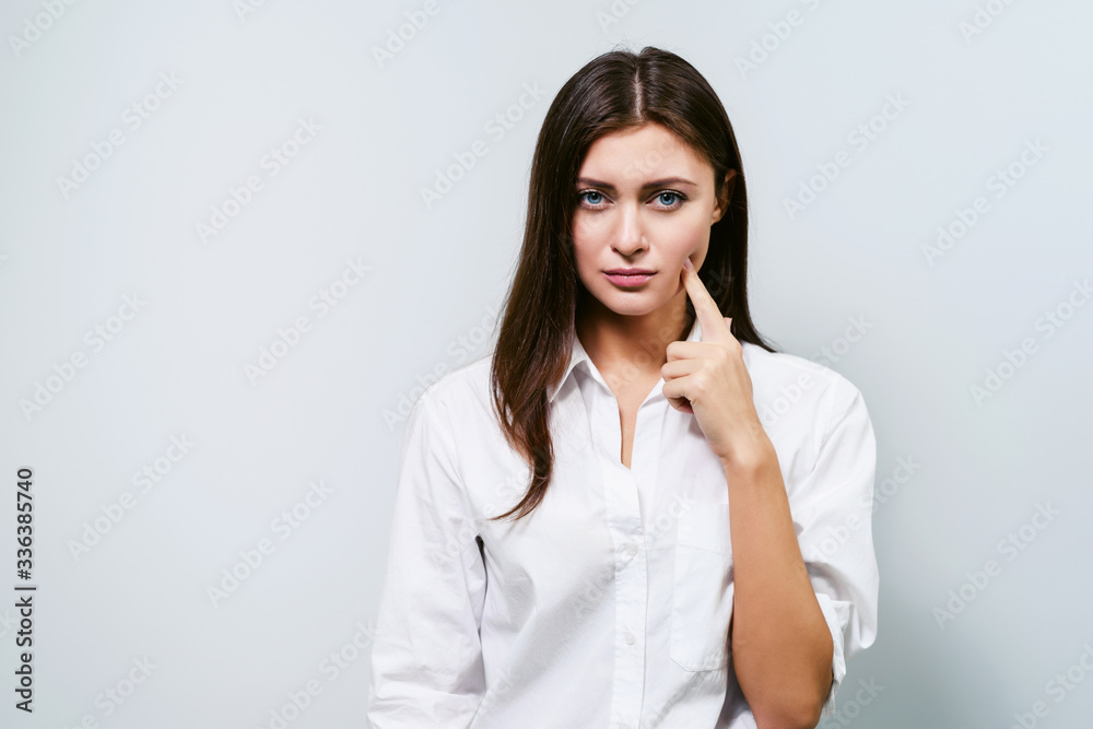 Woman has a toothache. Young brunette girl on a white background shows different emotions Woman has a toothache. Young brunette girl on a white background shows different emotions