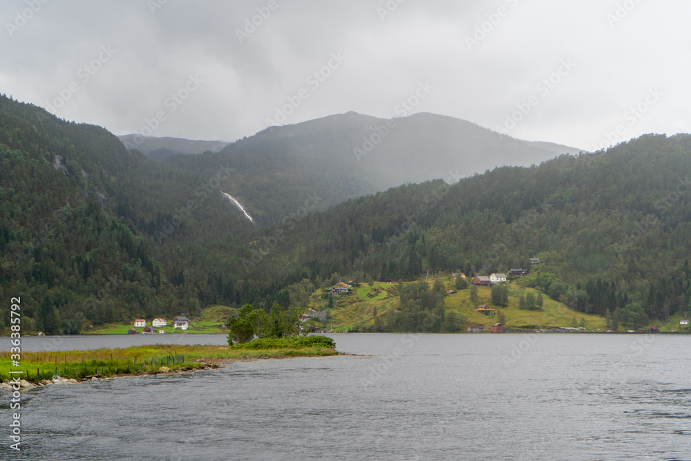 Villages of Norway in front of the Mountain: photo was taken in August 2019 during the Mostraumen fjord cruise. 