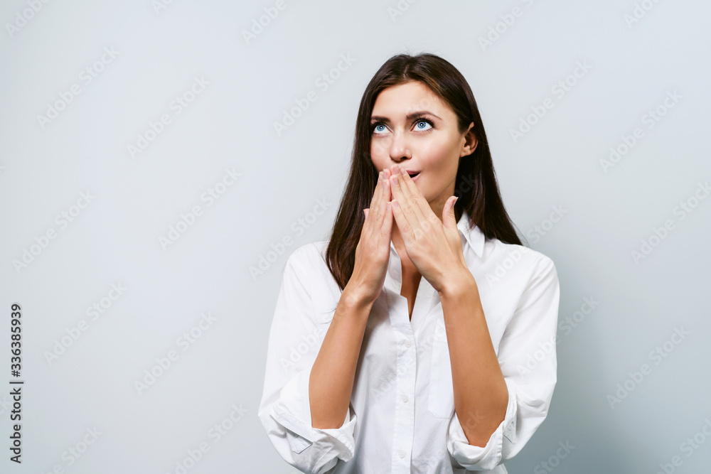 Woman is surprised. Young brunette girl on a white background shows different emotions. Wonderment. Woman is surprised. Young brunette girl on a white background shows different emotions. Wonderment.