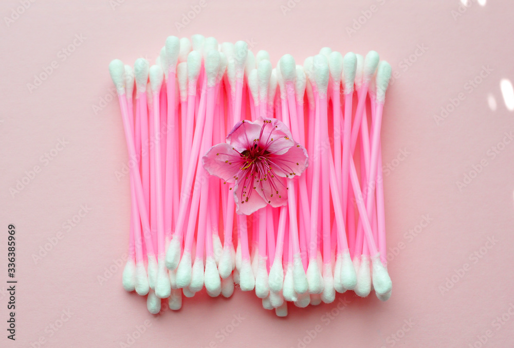 Pink ear sticks and pink flower on a pink background, cosmetology, medicine, body care, beauty Pink ear sticks and pink flower on a pink background, cosmetology, medicine, body care, beauty