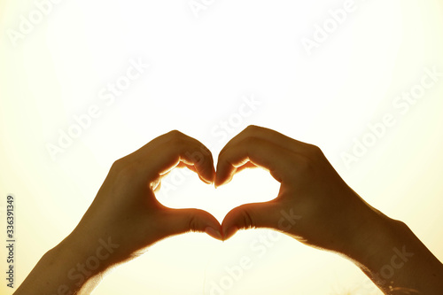 Closeup of cupping hands into a heart shape with bright background. Symbol of love. Praying to God for peace, and praying for coronavirus infected people in the world