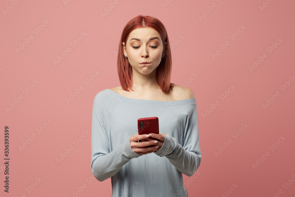 Serious woman with phone in her hands standing in studio Serious woman with phone in her hands standing in studio