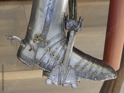 Close up of armored boot with spur on saddle  stirrup . Medieval equipment of armored knight