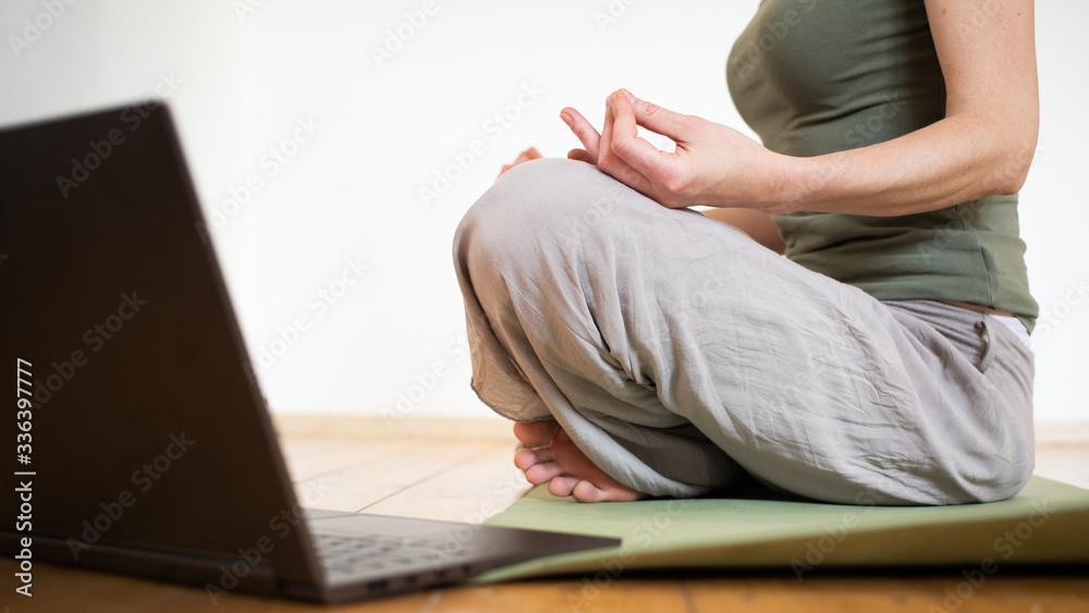 woman with laptop doing yoga at home coronavirus