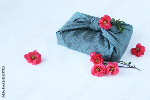 赤いボケの花と風呂敷包み © HanaPhoto