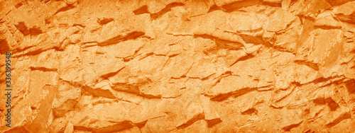 Abstract red orange background. Toned rock texture. Banner with a bright orange stone texture. The combination of bright color and rough surface of the mountain.