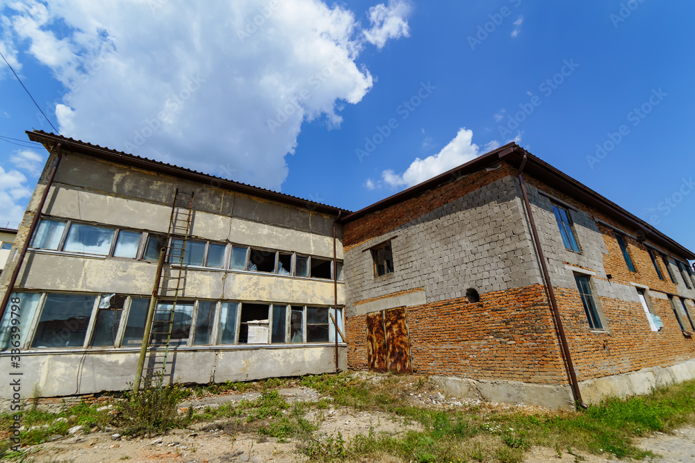 An old abandoned stone building with broken windows. Old warehouse, storehouse, factory. An old abandoned stone building with broken windows. Old warehouse, storehouse, factory.