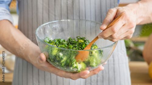 Man mixing delicious superfood salad ingredients with wooden spoon