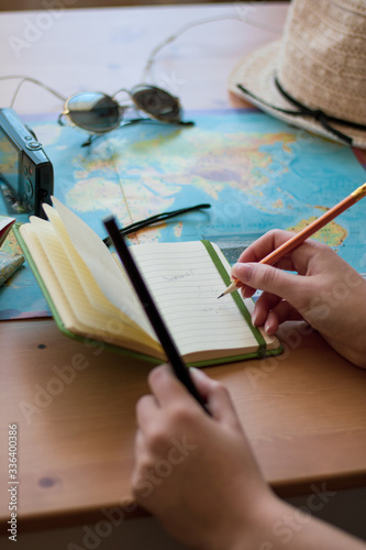 Young women planning a vacation trip and looking for information or booking a hotel using smartphone and writing notes.
  Selective focus, shallow depth of field,
  traveling concept.