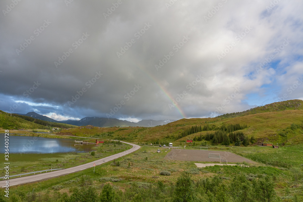 Fototapeta premium road to Unstad under colorful Rainbow in Lofoten islands, Norway, selective focus