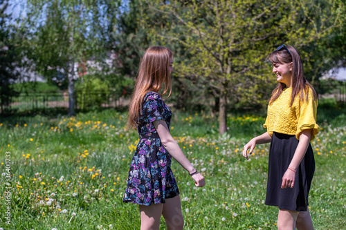Young girls have fun time in the park.  The sisters communicate and share secrets. Happy sisters are enjoying a warm spring day © Liubov Kartashova